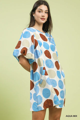 Women wearing a dotted brown and blue dress against a green background.
