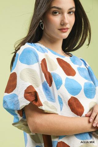 Woman wearing a colorful polka dot top against a light green background