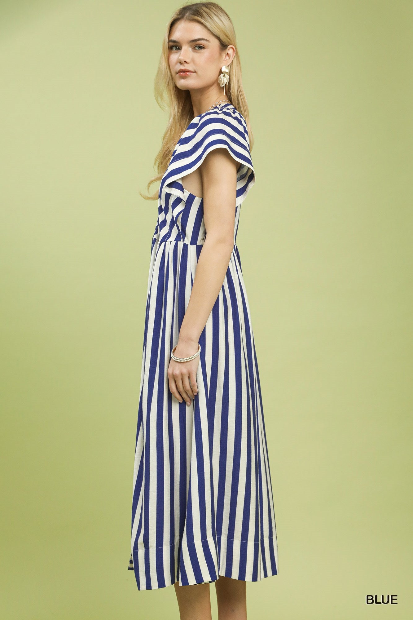 Woman wearing a blue and white striped dress on a green background