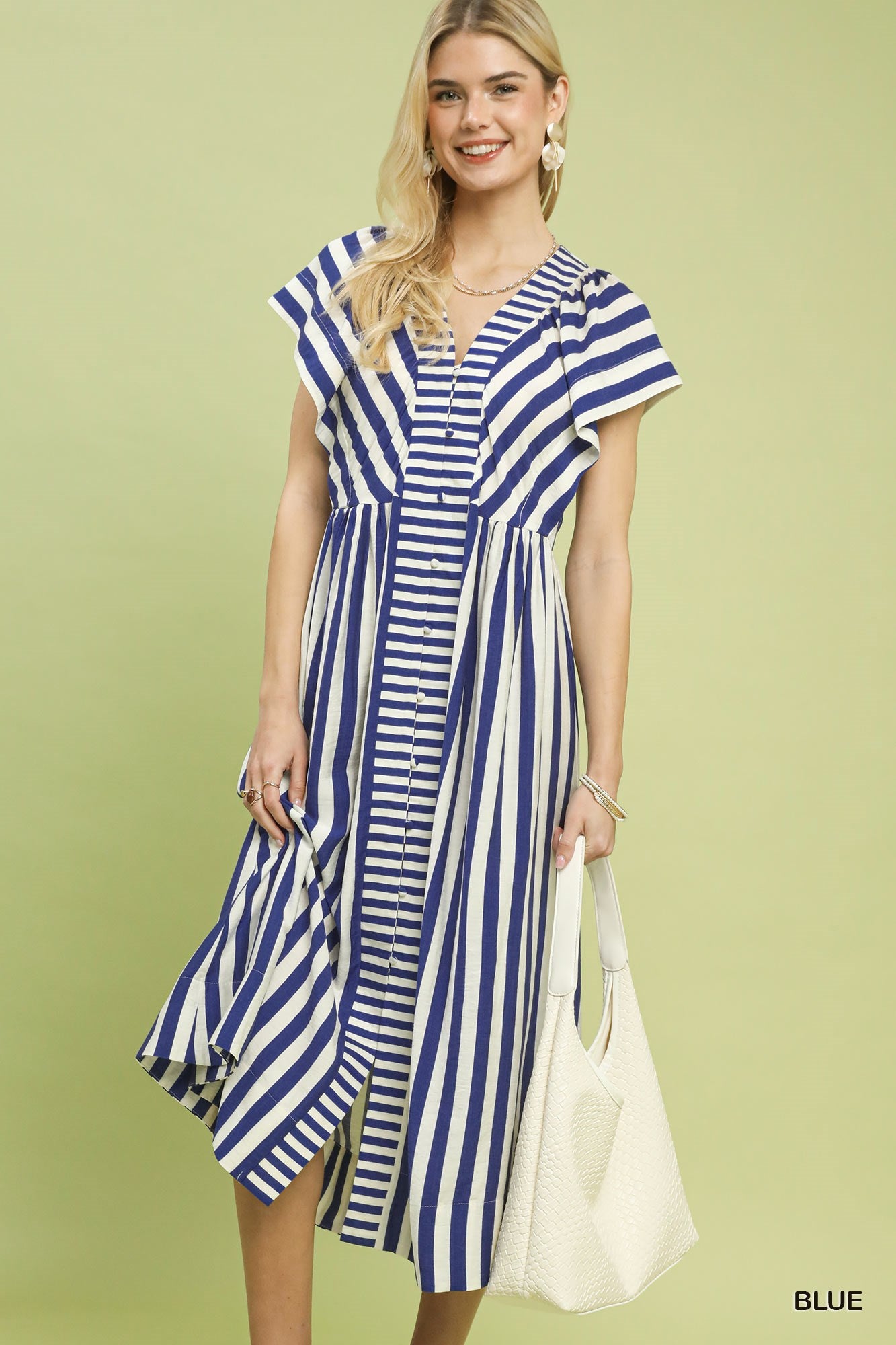 Woman wearing a blue and white striped dress against a light green background
