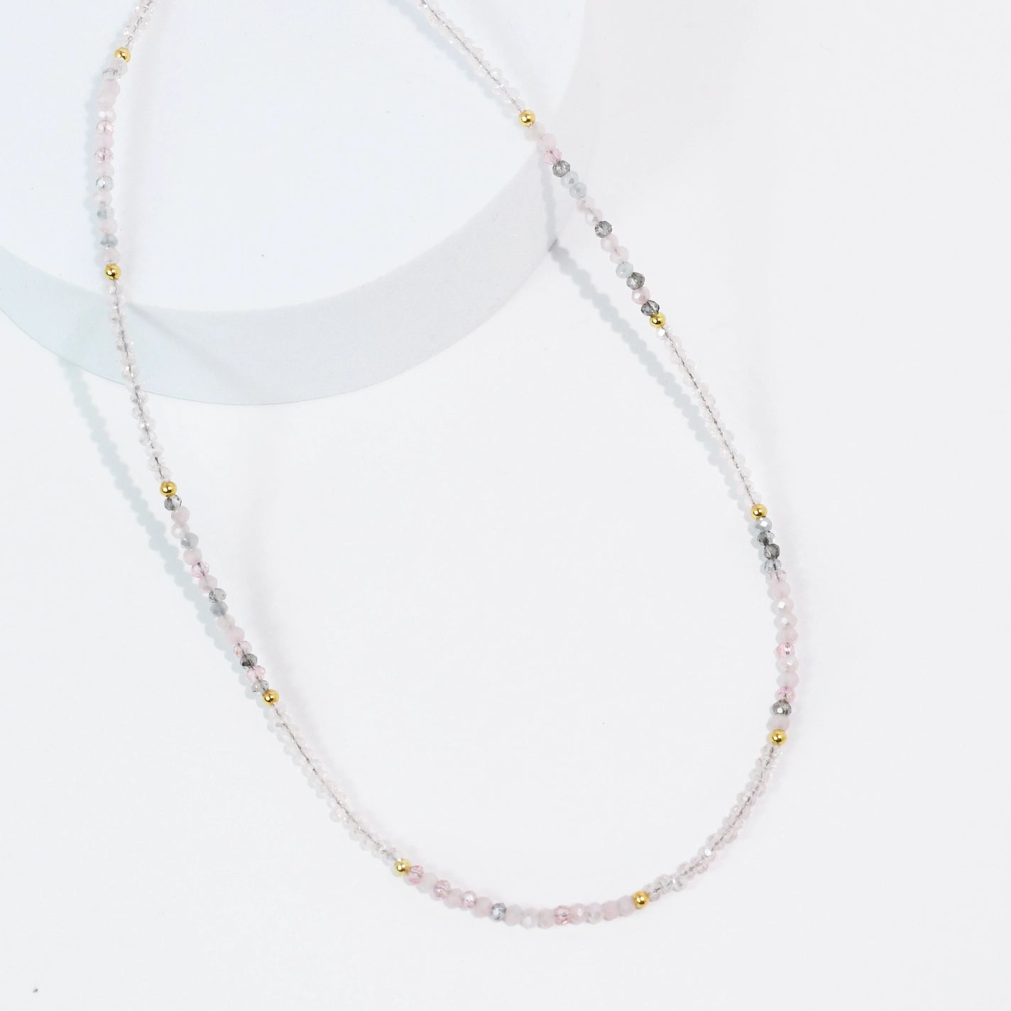 A dainty and simple pink and grey beaded necklace. 