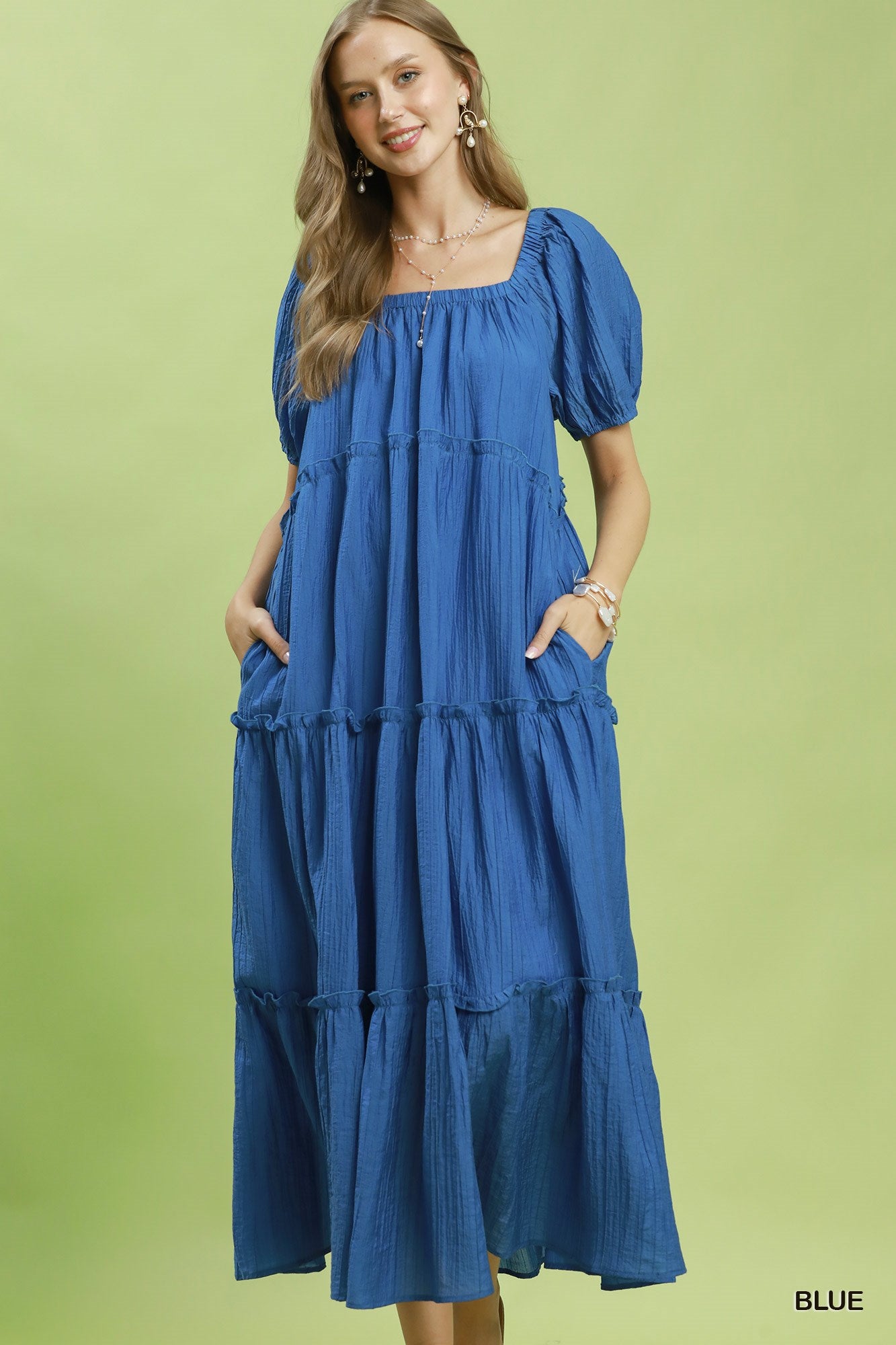 Woman wearing a blue dress with puff sleeves against a green background