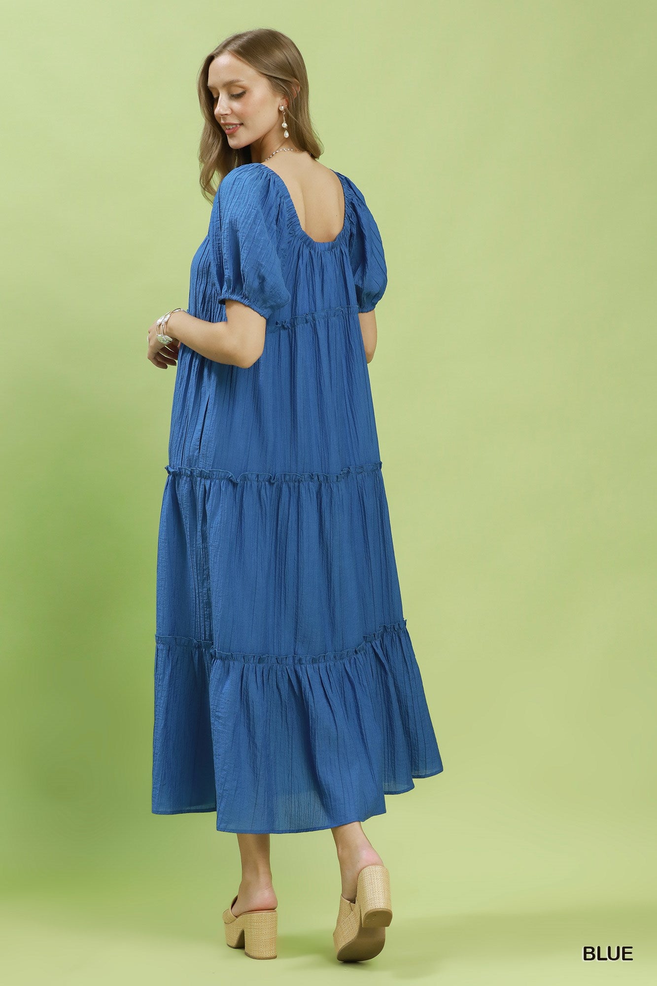 Woman wearing a blue dress on a green background