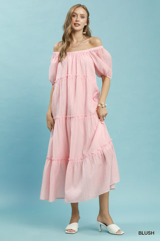 Women wearing a pink maxi dress against a blue background.