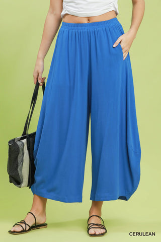 Person wearing blue wide-leg pants with a black and gray bag on a green background