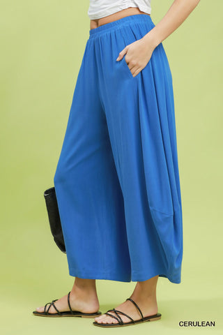 Person wearing blue wide-leg pants on a green background