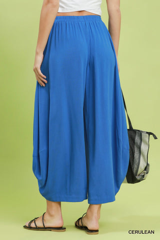 Person wearing blue wide-leg pants on a green background