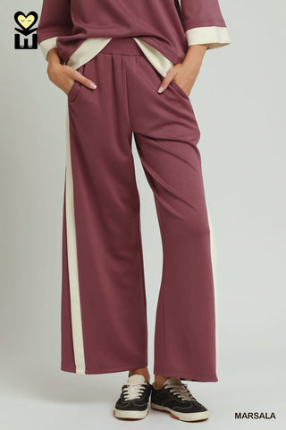 Maroon pants with white stripes worn by a person on a plain background