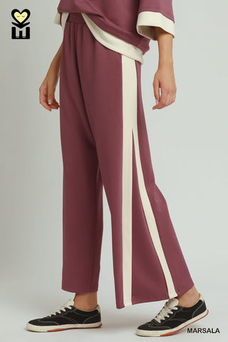 Maroon pants with a white stripe worn by a person on a plain background