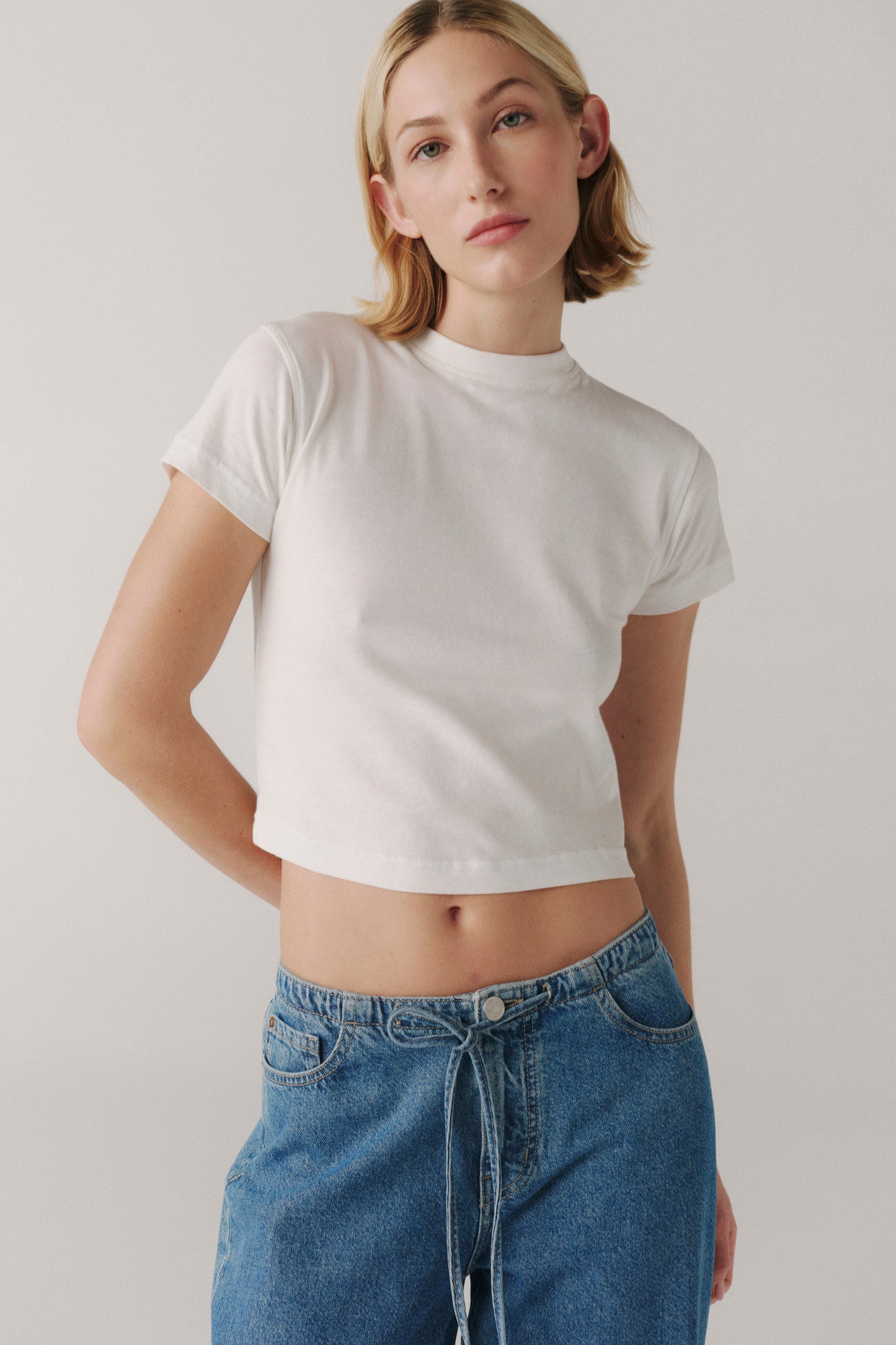 Person wearing a white t-shirt and blue jeans against a plain background