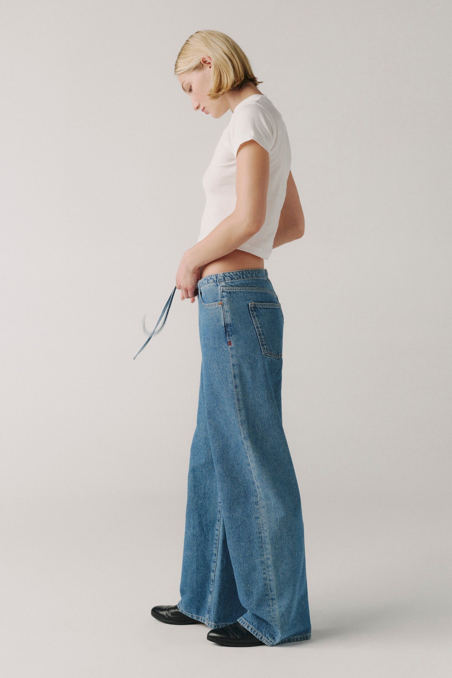 Person wearing a white top and blue jeans on a plain background