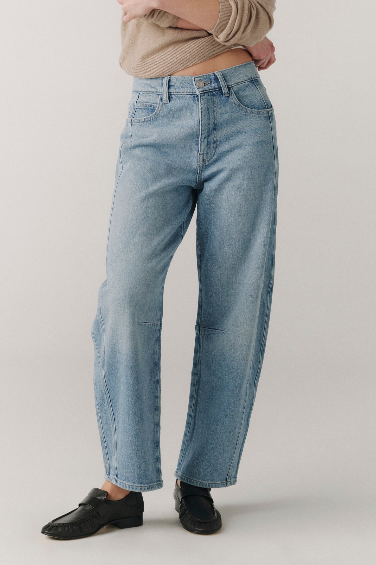 Person wearing light blue jeans on a plain background