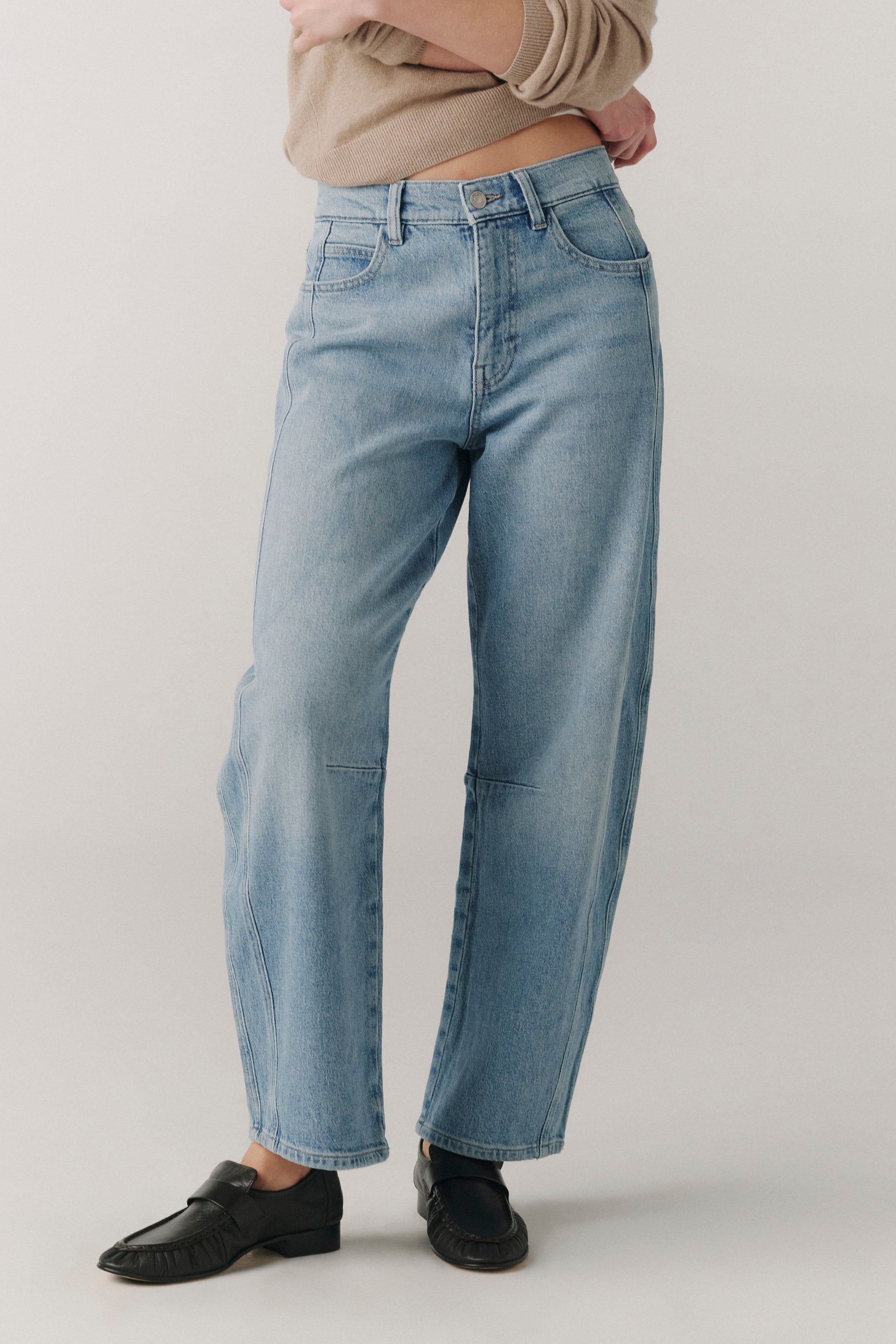 Person wearing light blue jeans on a plain background