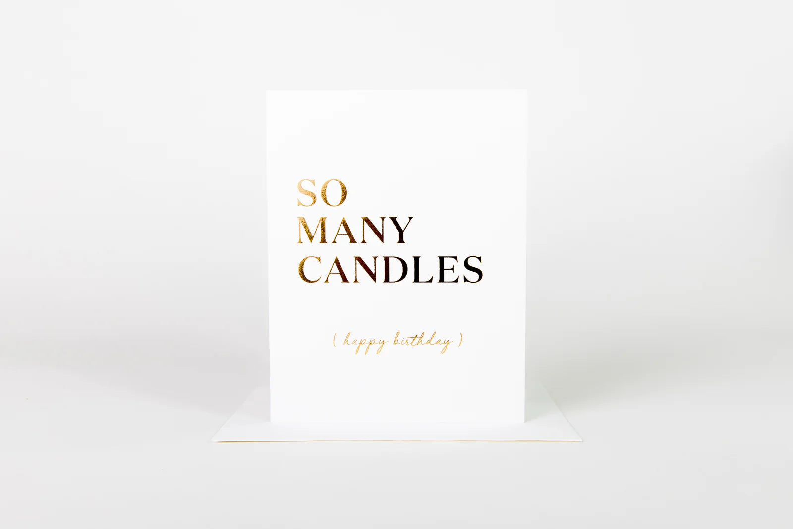White card with gold text 'SO MANY CANDLES' on a white background