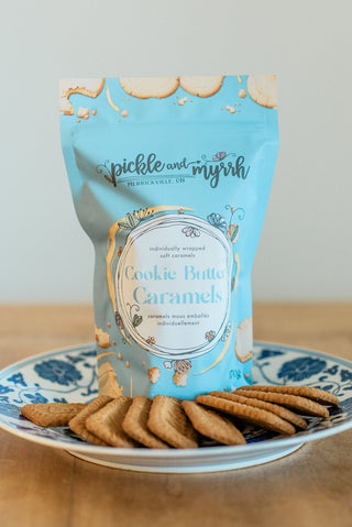 Packaging of 'Cookie Butter Caramels' by Pickle and Myrrh on a decorative plate with cookies.