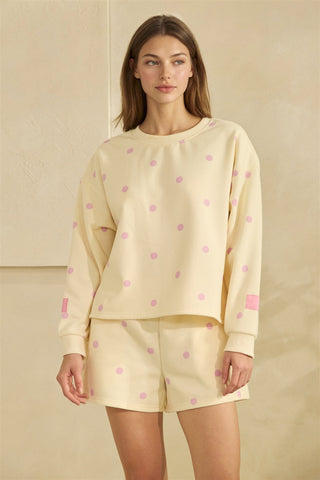 Woman wearing a light yellow outfit with pink polka dots on a beige background