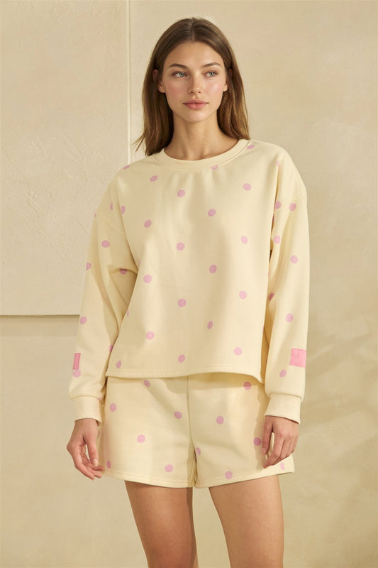 Woman wearing a light yellow outfit with pink polka dots on a beige background