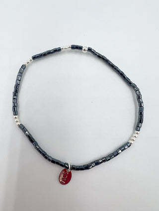 Necklace with black beads and a red pendant on a light gray background