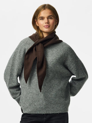 A woman wearing a heather gray knit sweater and a dark brown scarf, photographed against a plain light gray studio background.