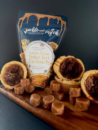 Pecan pralines and caramels with a package labeled 'Pickle and Myrtle' on a dark background