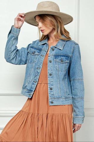 Woman wearing a denim jacket and beige hat against a white background