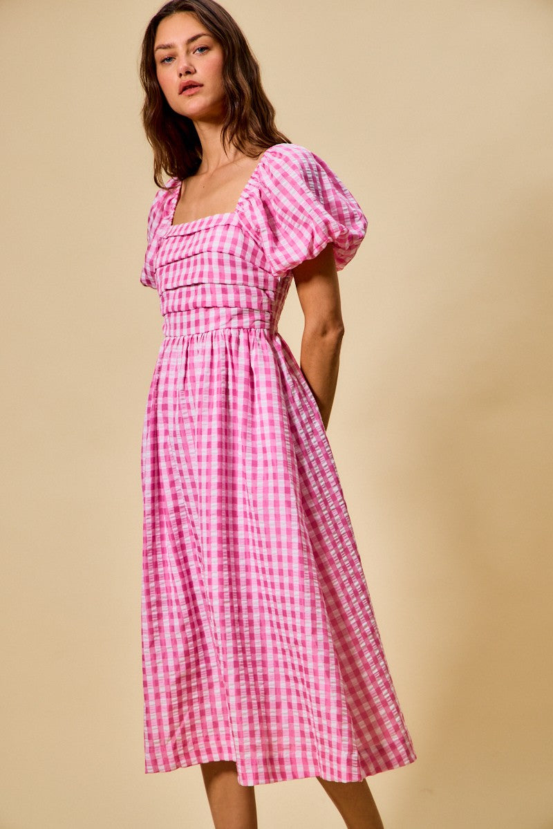 Woman wearing a pink checkered dress against a beige background