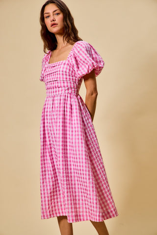 Woman wearing a pink checkered dress against a beige background