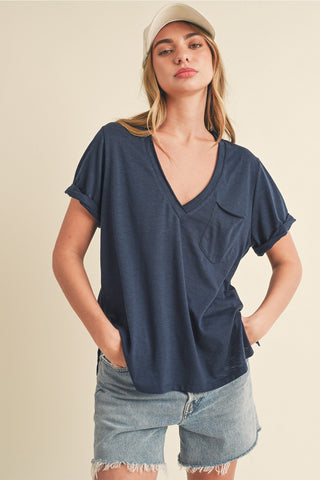 Woman wearing a navy blue top and denim skirt against a beige background