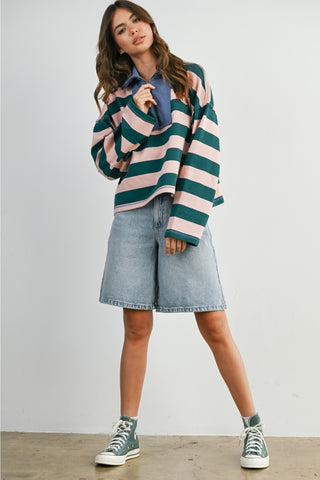 Person wearing a striped sweater, denim shirt, and shorts with sneakers on a plain background