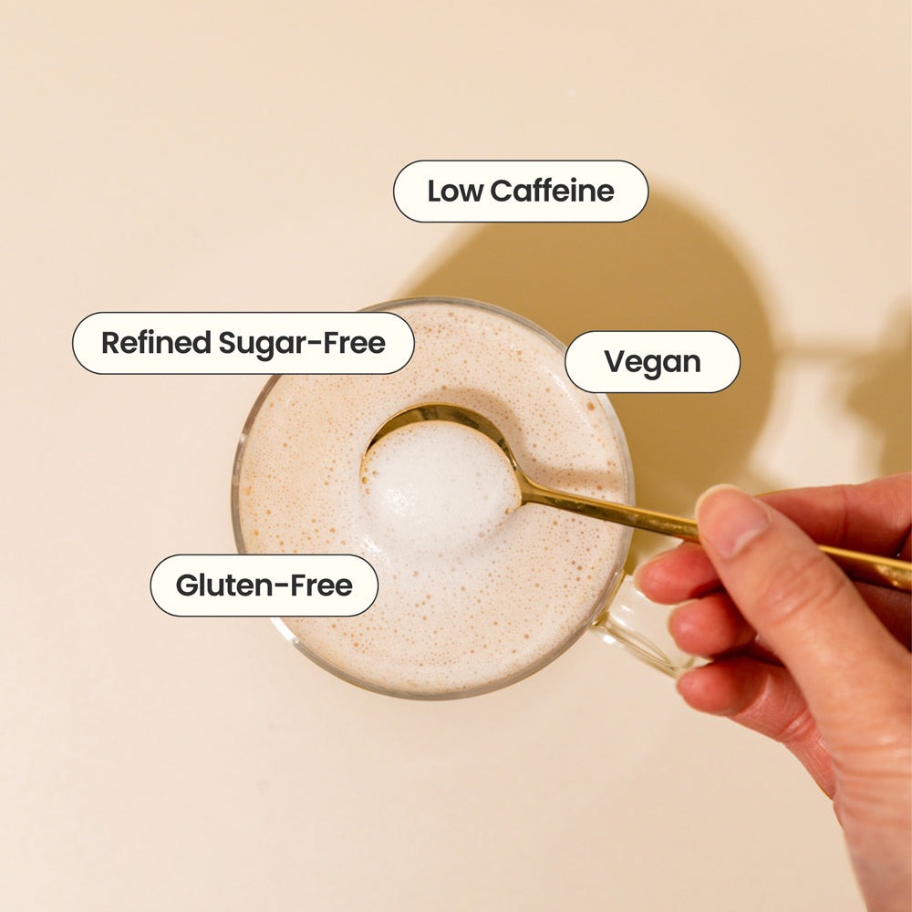 Glass of low caffeine, refined sugar-free, vegan, and gluten-free beverage with a hand holding a spoon.