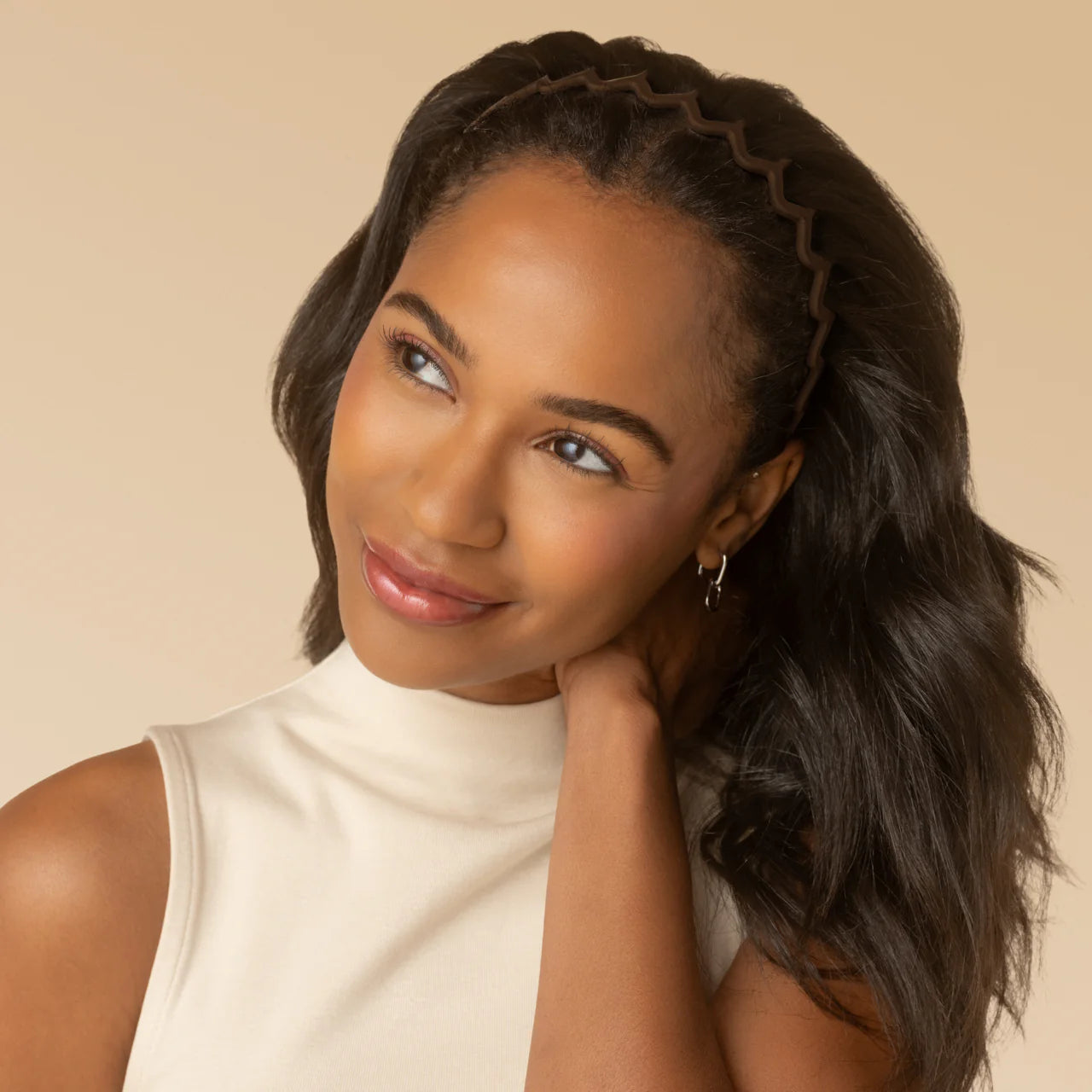 Woman with braided hair wearing a white top against a beige background