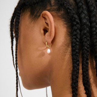 gold hoops with a pearl drop on a women's ear.