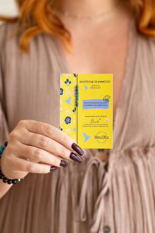 Person holding a yellow card with blue butterfly design and text.
