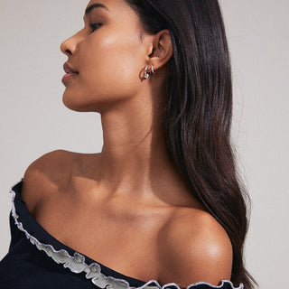Woman wearing a black off-shoulder top with lace details on a neutral background