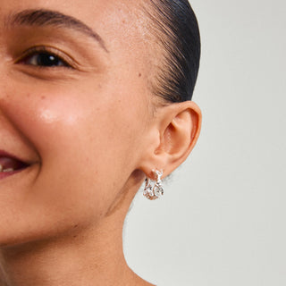 Close-up of a woman wearing a silver earring on a plain background