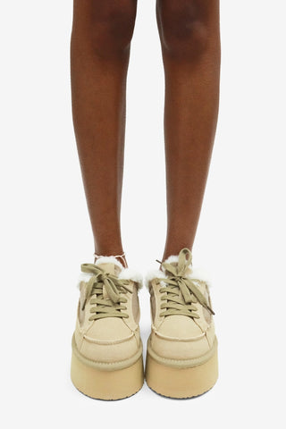 Beige sneakers worn with brown tights on a white background