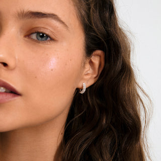 Close-up of a woman wearing a diamond earring with a neutral background