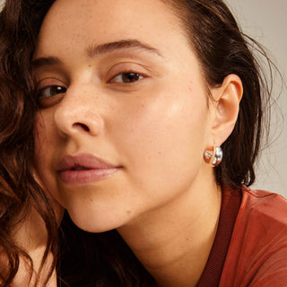 Close-up of a woman wearing earrings with a neutral background