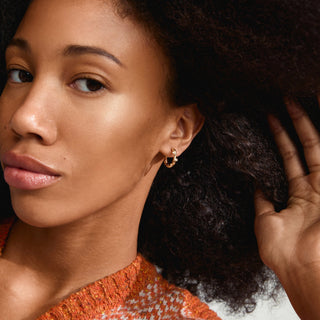 Woman with styled hair and orange top, close-up