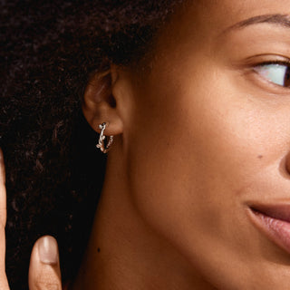 Close-up of a person wearing a small hoop earring.