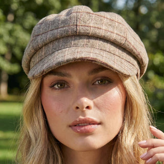 Woman wearing a plaid cap with a blurred green background