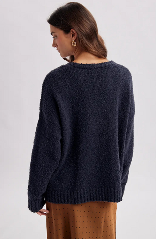 Women wearing a navy cardigan against a neutral background.