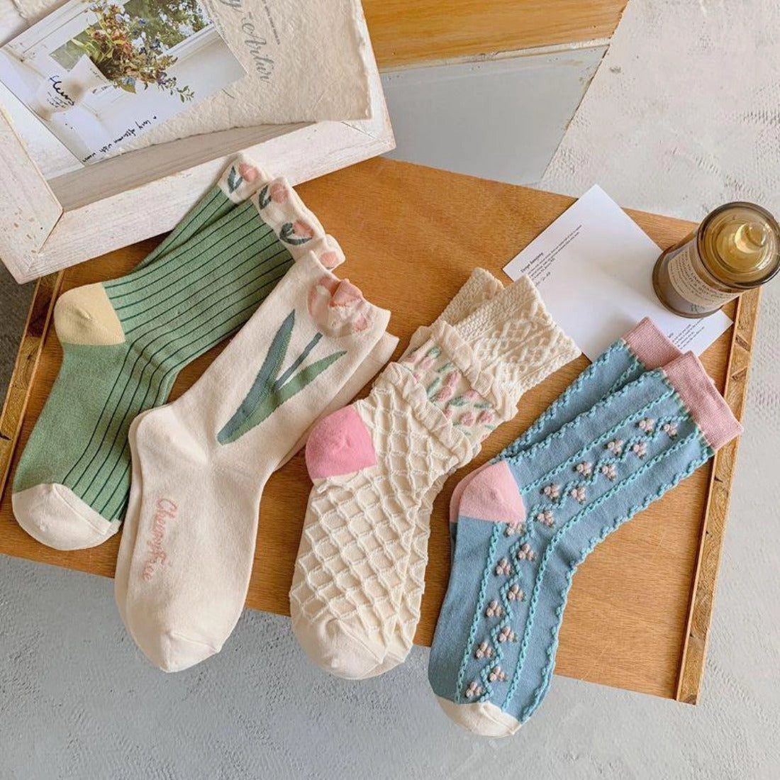 Four pairs of colorful socks on a wooden tray with a neutral background