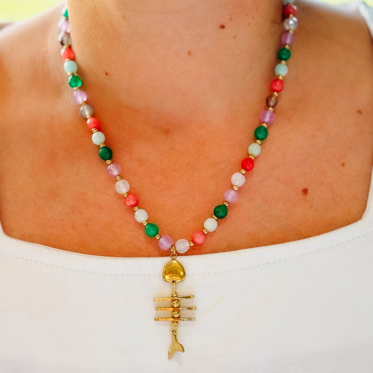 women wearing a beaded necklace with a fishbone gold prendant .