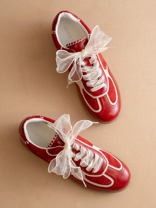 Red sneakers with white laces on a beige background