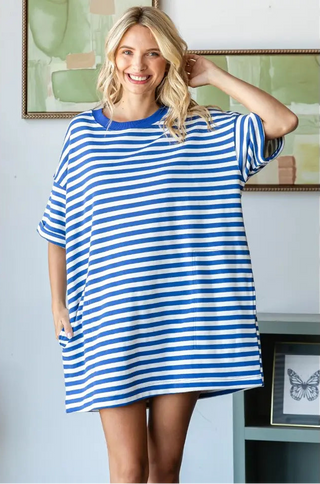 Woman wearing a blue and white striped dress in a room with light blue walls.