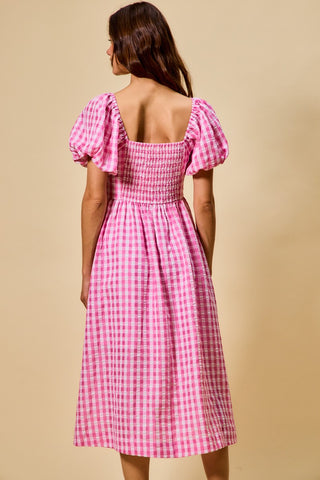 Woman wearing a pink checkered dress against a beige background