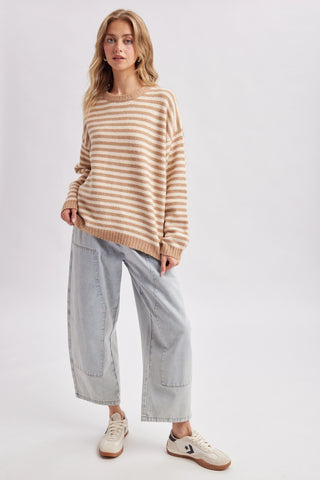 Women wearing a striped beige sweater against a neutral background.
