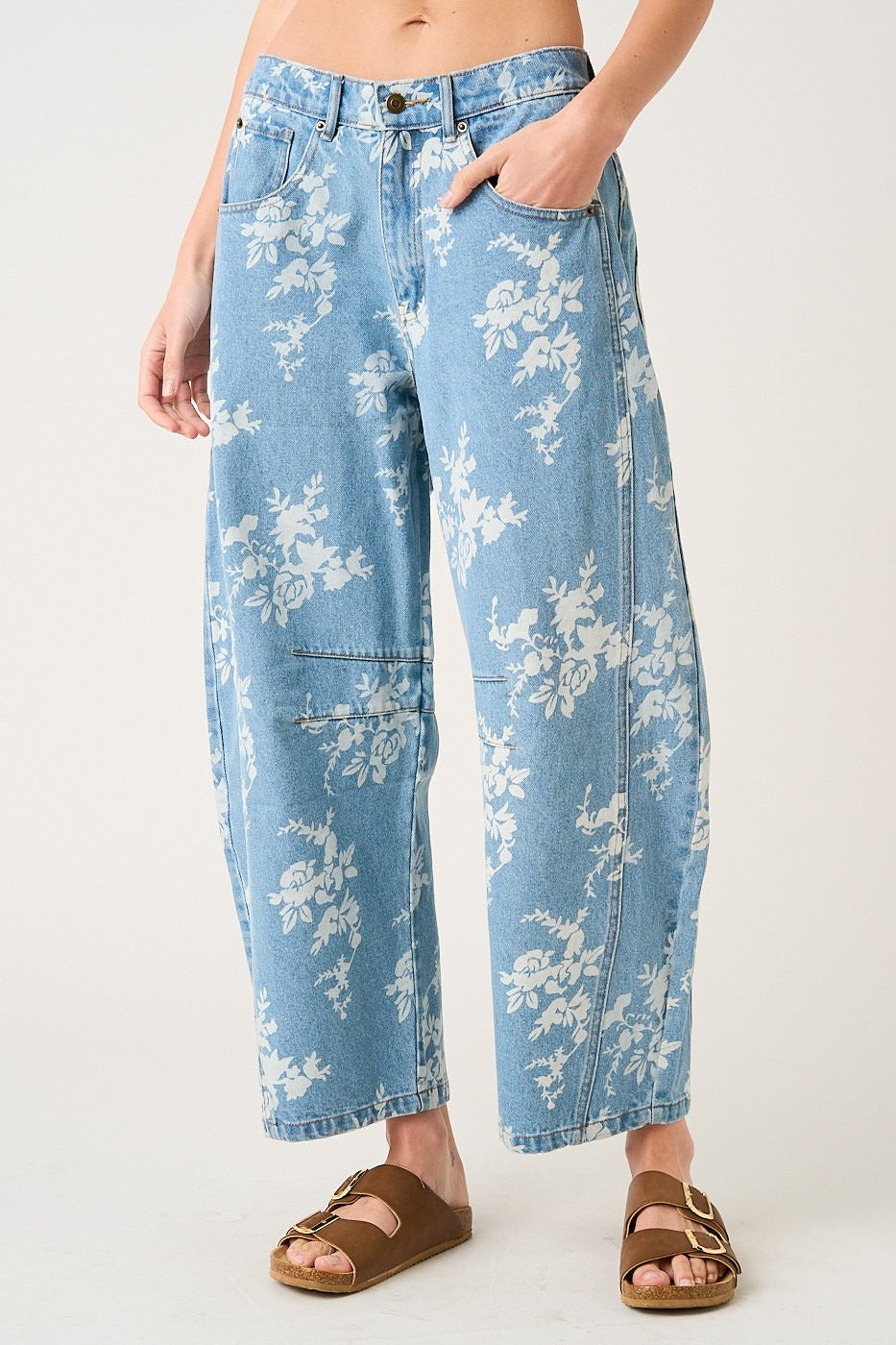 Light blue jeans with white floral patterns worn by a person on a plain background