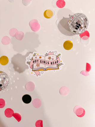 Sticker with 'Hot Girls Read' design on a surface with confetti and disco balls.